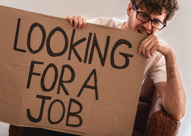 istock depressed jobless man holding a looking for a job cardboard for unemployment problem concept. 1307180033