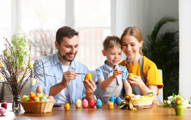 istock Delighted family: father, mother and son painting Easter eggs together 1307181383