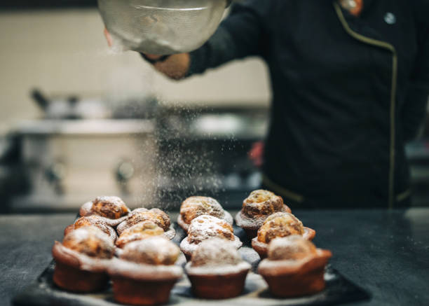 istock Female Chef sprinkling powdered sugar on muffins 1307181598