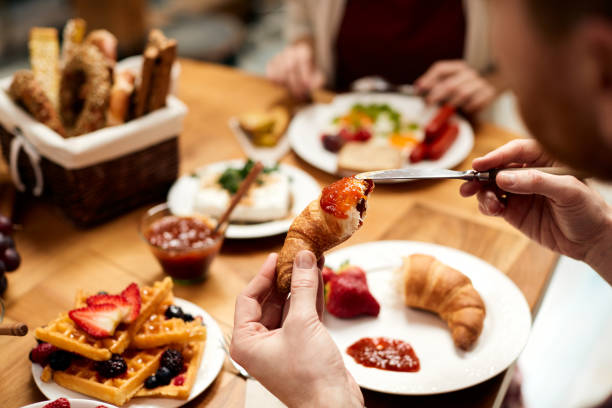 istock Close-up of man having croissant with jam for breakfast. 1307182632