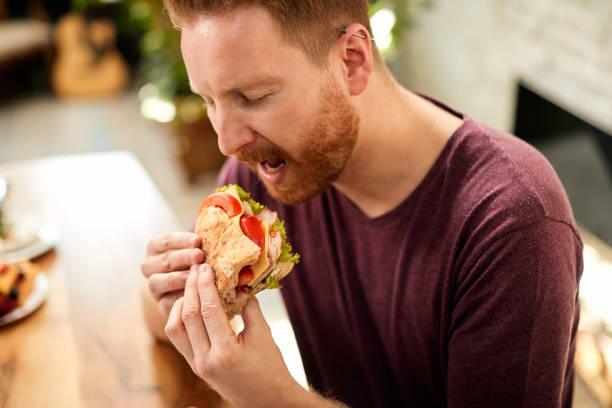 istock Young man enjoying while eating sandwich at home. 1307182690