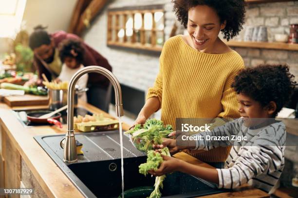 Happy Black Mother And Son Watching Salad While Preparing Food In The Kitchen Stock Photo - Download Image Now