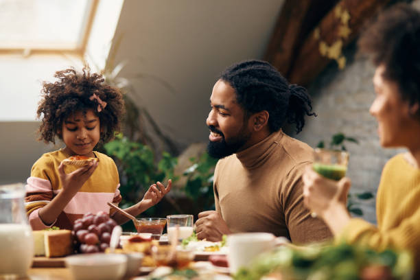 istock Happy African American father talking to daughter during breakfast at dining table. 1307188082