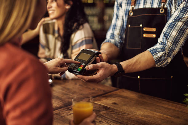 istock Close-up woman entering pin at credit card reader while paying in a cafe. 1307190636