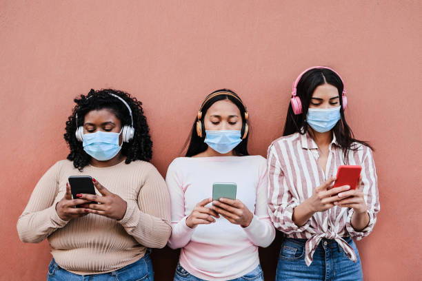 istock Young multiracial people wearing safety masks while using mobile phones outdoor - Main focus on center girl 1307190790