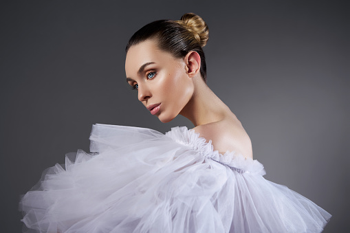 Portrait of a Romantic beauty Woman in light dress. Natural cosmetics, beautiful smooth facial skin, hair pulled back in a bun, art body