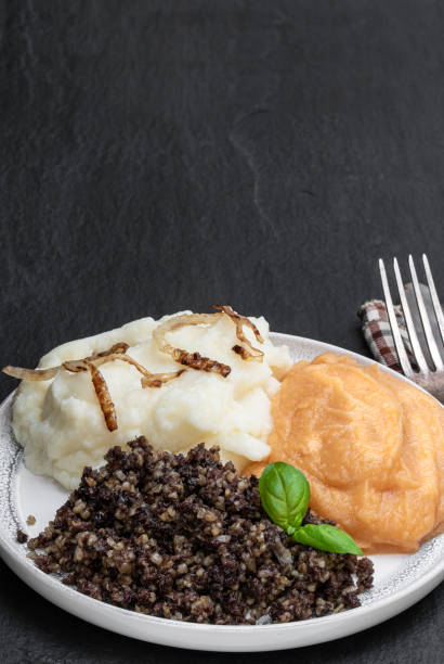 Traditional Scottish haggis with neeps and tatties on black stone background Traditional  Scottish haggis with neeps and tatties on black stone background haggis stock pictures, royalty-free photos & images