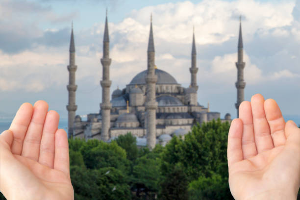 praying woman hand in front of mosque background. Istanbul, Turkey. Sultan Ahmet Camii named Blue Mosque .Woman hands praying for blessing from god on sunset background