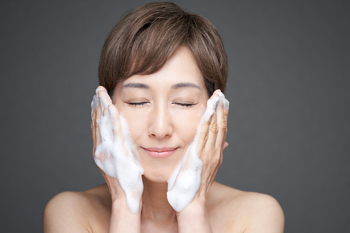 Middle-aged Japanese woman washing face with foam