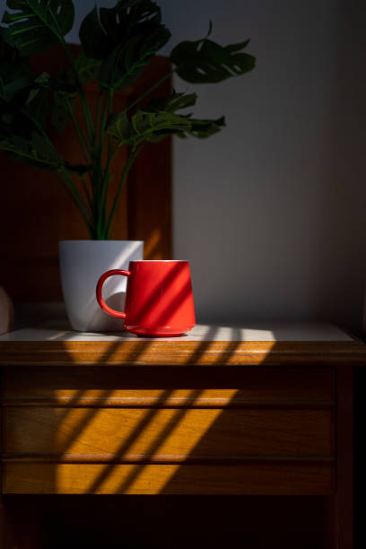 Image of a red coffee mug on top of a night stand in bedroom