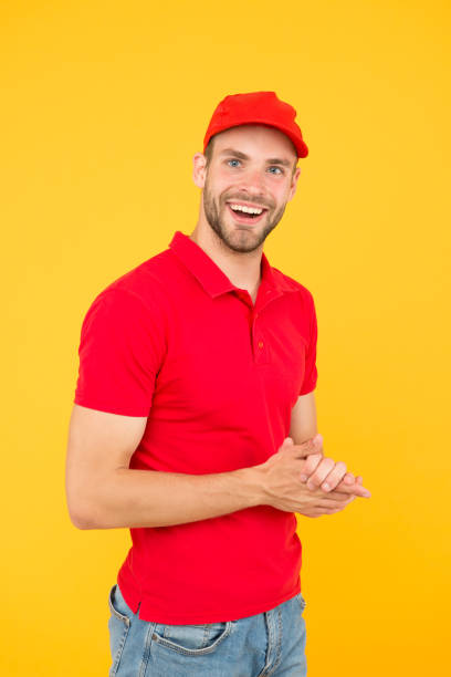 istock Postman delivery worker. Man red cap yellow background. Delivering purchase. Already ready. Easing your business. Service delivery. Salesman and courier career. Courier and delivery service 1307199003