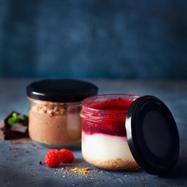 istock Two homemade easy cheesecakes in jars with chocolate mousse and raspberry curd sauce on a dark blue background. Healthy dessert. Selective focus. Homemade Raw Vegan Pudding. 1307199205