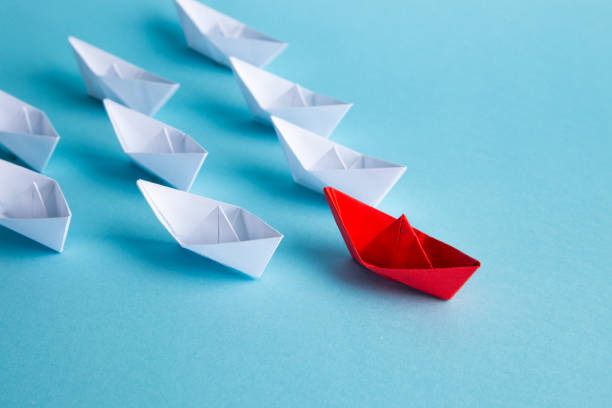 istock Leadership concept. Red leader paper ship leading among others on blue background. 1307200126