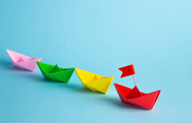 istock Leadership concept. Red leader paper ship leading among others on blue background. 1307200167