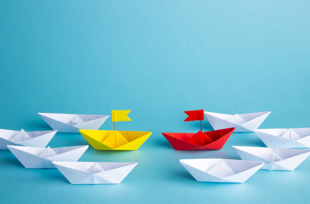 istock Leadership concept. Red leader paper ship leading among others on blue background. 1307200267