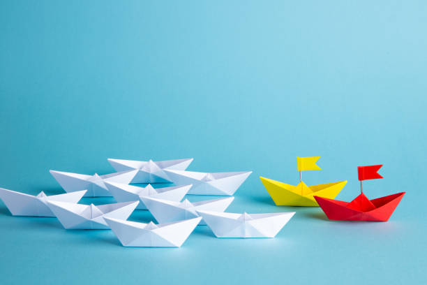 istock Leadership concept. Red leader paper ship leading among others on blue background. 1307200345