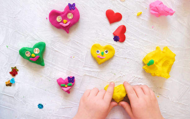 istock Child playing with colorful modeling clay with  beads and sequins and sculpting heart figure. Home Education game with clay. 1307201636