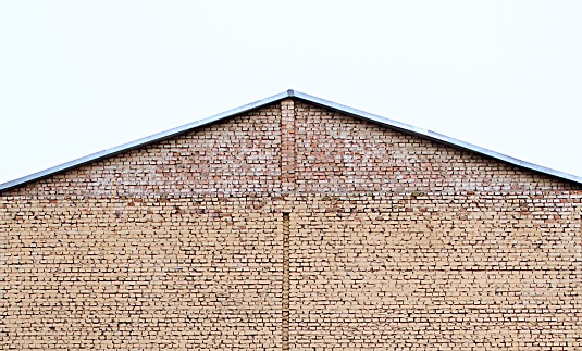 brick house without windows. side view of roof top on grey sky background