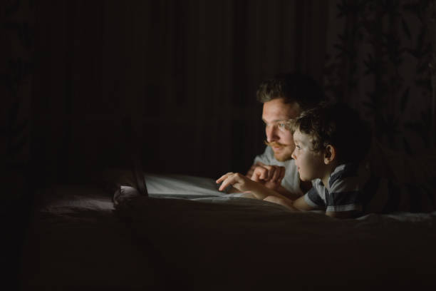 istock Father and son using laptop by night at home on the bedroom. 1307203219