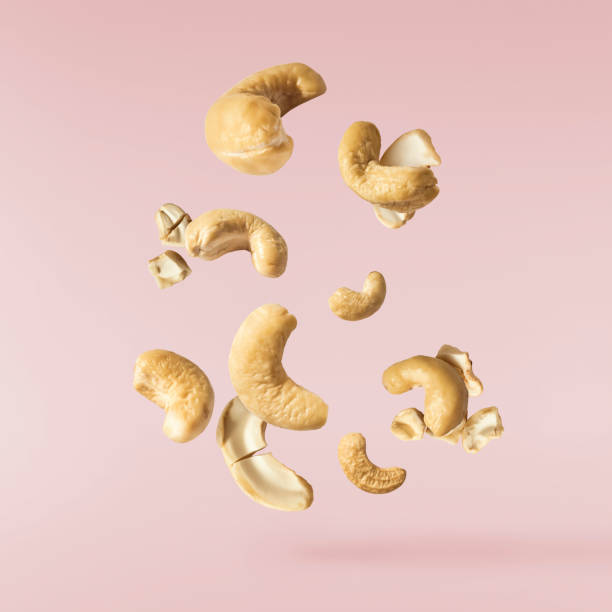 fresh cashew nut falling in the air Fresh tasty Cashew nuts falling in the air isolated on pink background. Food levitation concept. High resolution image. cashew photos stock pictures, royalty-free photos & images