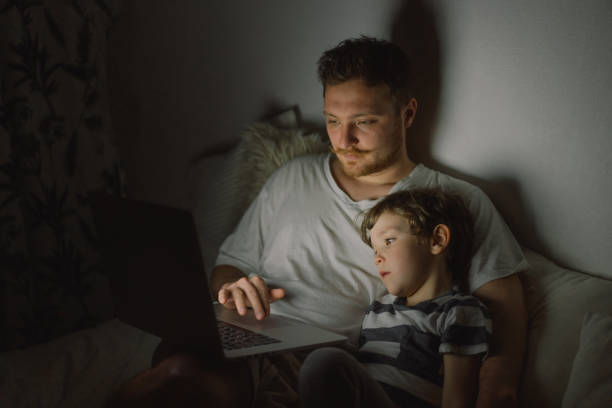 istock Father and son using laptop by night at home on the bedroom. 1307203647