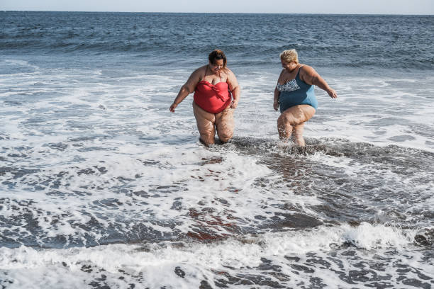 istock Curvy women playing on the beach having fun on summer time - Focus faces 1307206468