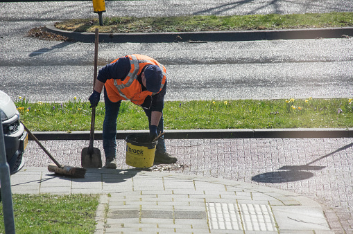 Brunssum, the Netherlands, - March 15, 2021. Municipal worker cleaning the street in the morning sun.