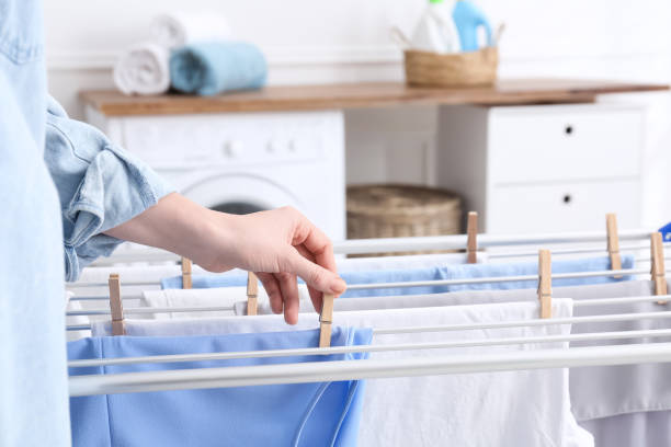istock Woman hanging clean laundry on drying rack in bathroom, closeup 1307208099