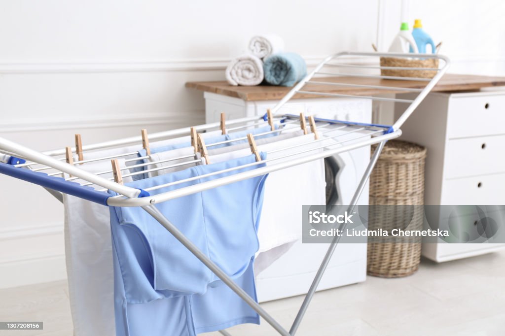 Clean laundry hanging on drying rack indoors Clothesline Stock Photo
