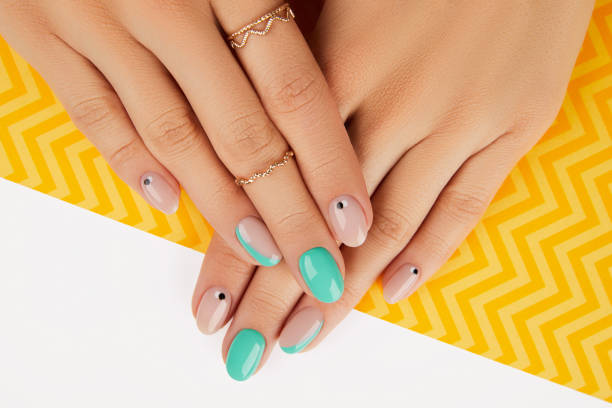 istock Womans hands with trendy turquoise manicure on yellow background 1307211140