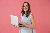 Cheerful young woman using laptop computer. Looking camera.