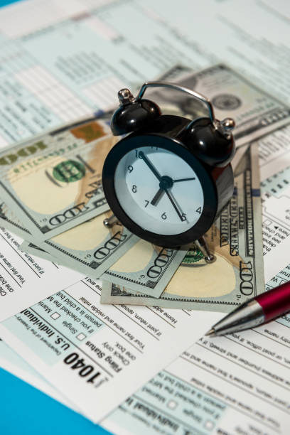 istock tax forms 1040 with clock pen and dollar bills 1307212591