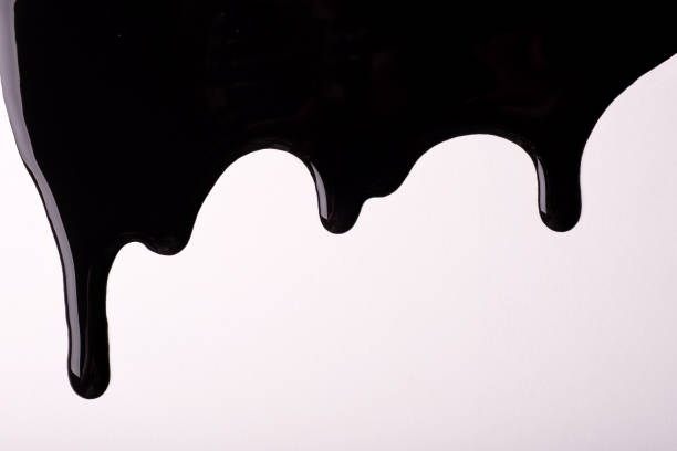 istock Black liquid drops of paint color flow down on isolated white background. Abstract dark backdrop with fluid drip pattern 1307212949