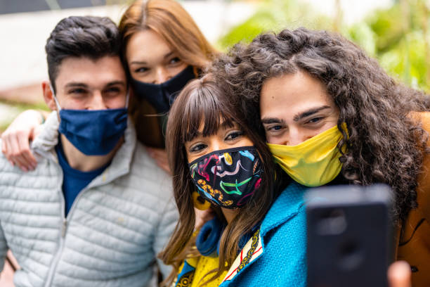 istock two happy couples making selfie with facemask, group of multiethnic friends having fun on social media, new normal lifestyle in Corona Virus outbreak 1307213183