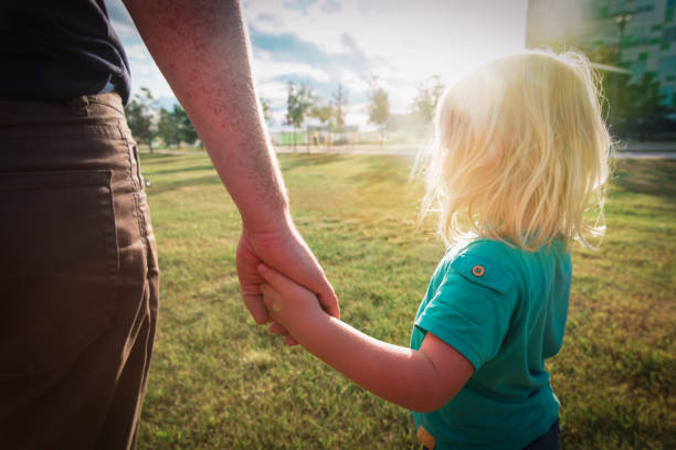 Father with a small daughter holding hands at sunset Father with a small daughter holding hands at sunset nature kid holding fathers hand stock pictures, royalty-free photos & images