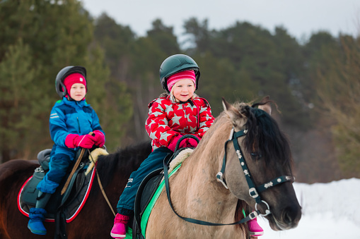 little girls on horse ride in winter nature, active lifestyle