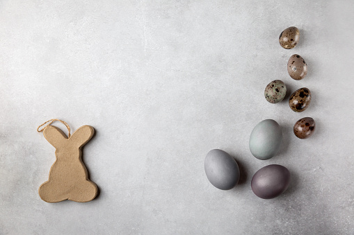 Colorful Easter eggs and decorative bunny on gray background. Happy Easter concept.  Top view, flat lay, copy space.
