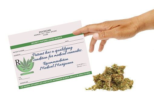 hand holding cannabis prescription and marijuana on white background