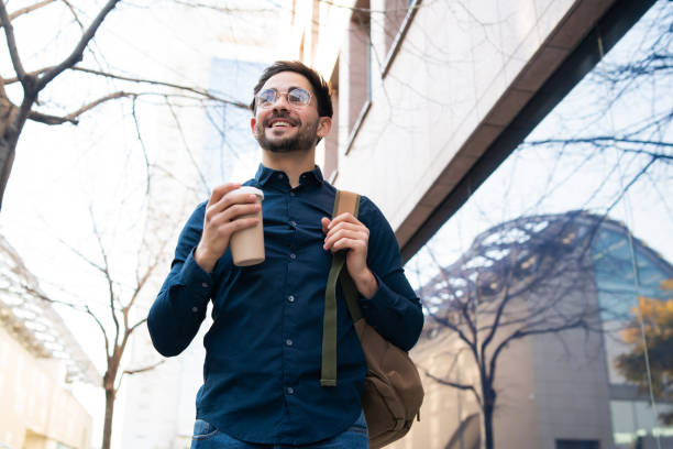 istock Young man holding a cup of coffee while walking outdoors. 1307216292