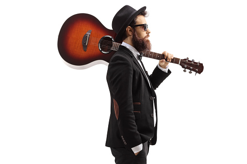 Bearded man carrying an acoustic guitar on his shoulder isolated on white background