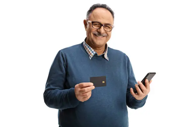 Photo of Cheerful elderly man with a credit card and a mobile phone smiling at camera