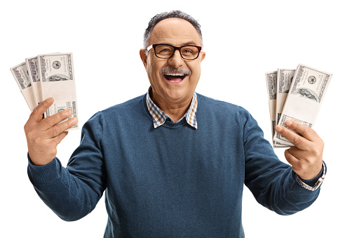 Excited and cheerful mature man holding us dollars and smiling isolated on white background