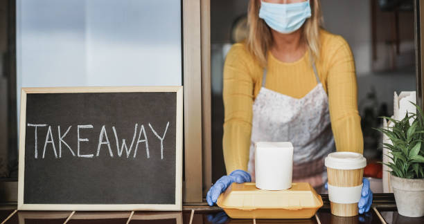 istock Young woman preparing delivery food inside takeaway restaurant while wearing safety mask - Focus on food 1307217618