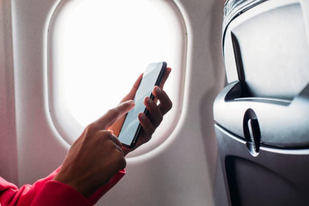 One last message before the flight Close up shot of an unrecognisable woman's hand while holding a phone in an airplane last stock pictures, royalty-free photos & images