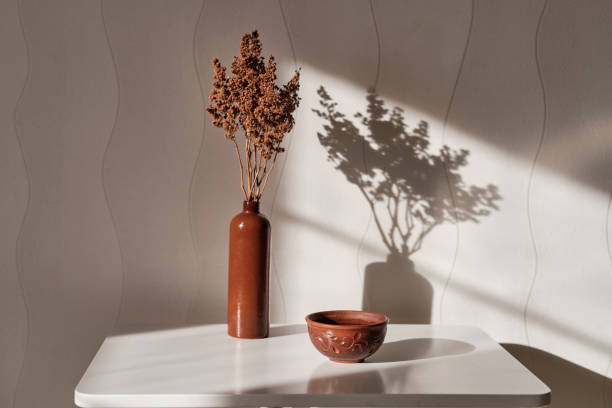 istock Interior composition. Clay brown cup with tea, clay vase with brown dried flowers on a white coffee table against a white wall background. 1307218069