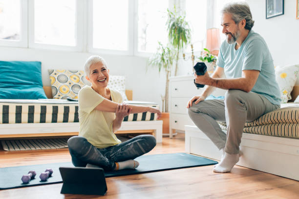 istock Senior woman doing exercises while senior man playing video games on couch 1307219514