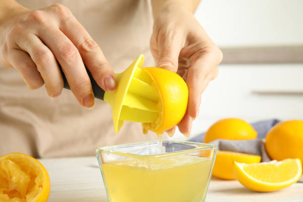 istock Woman squeezing lemon juice with reamer at table, closeup 1307221580
