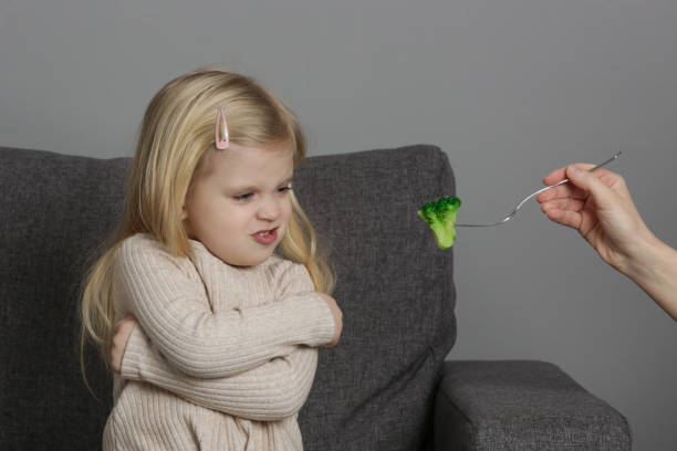 la petite fille ne veut pas manger de brocoli. enfant refusant de manger des légumes. - eating obsessive child toddler photos et images de collection