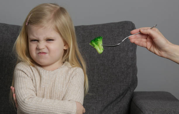 la petite fille ne veut pas manger de brocoli. enfant refusant de manger des légumes. - eating obsessive child toddler photos et images de collection