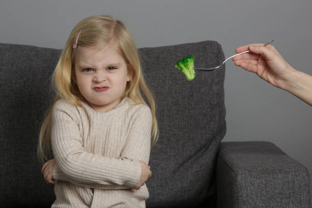 kleines mädchen will keinen brokkoli essen. kind weigert sich, gemüse zu essen. - eating obsessive child toddler stock-fotos und bilder